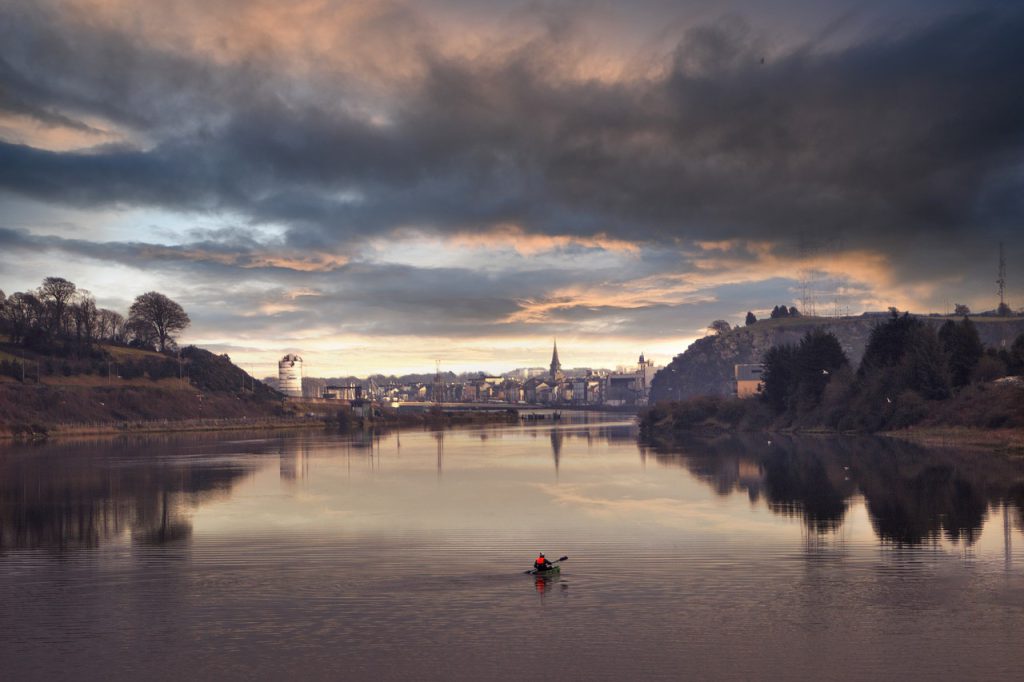 River Suir flowing through Waterford city at sunset with church spire and dramatic sky