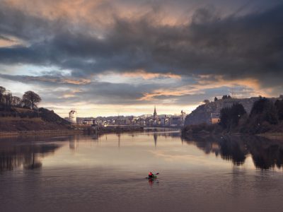 River Suir flowing through Waterford city at sunset with church spire and dramatic sky