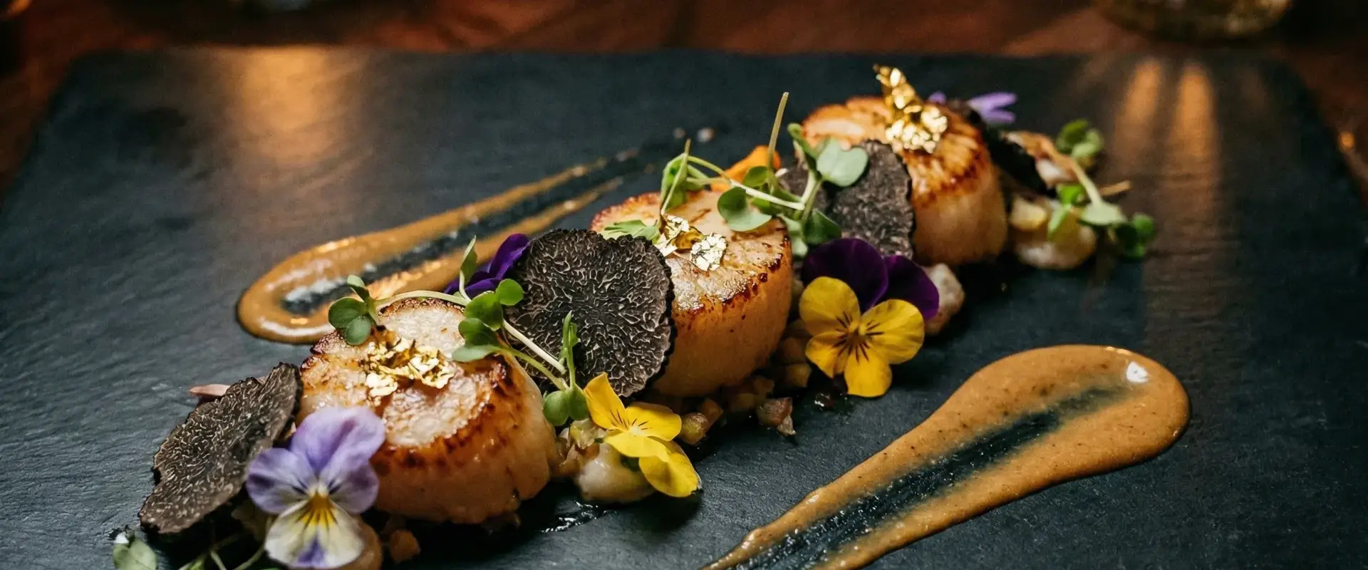 Fine dining dish with truffle and edible flowers on dark slate