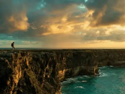 Coastal cliff overlooking turquoise ocean at sunset